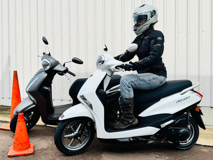 Person on a white scooter with another scooter and traffic cones in the background, getting a scooter licence in Darwin.