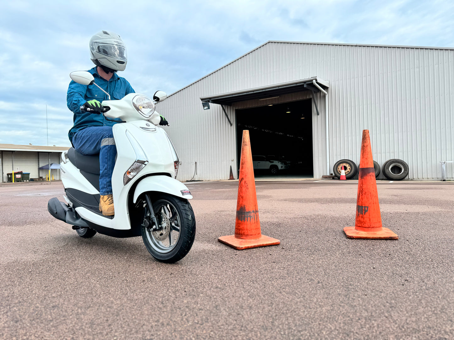 Person on a scooter with traffic cones in front of a building, getting a scooter licence in Darwin.